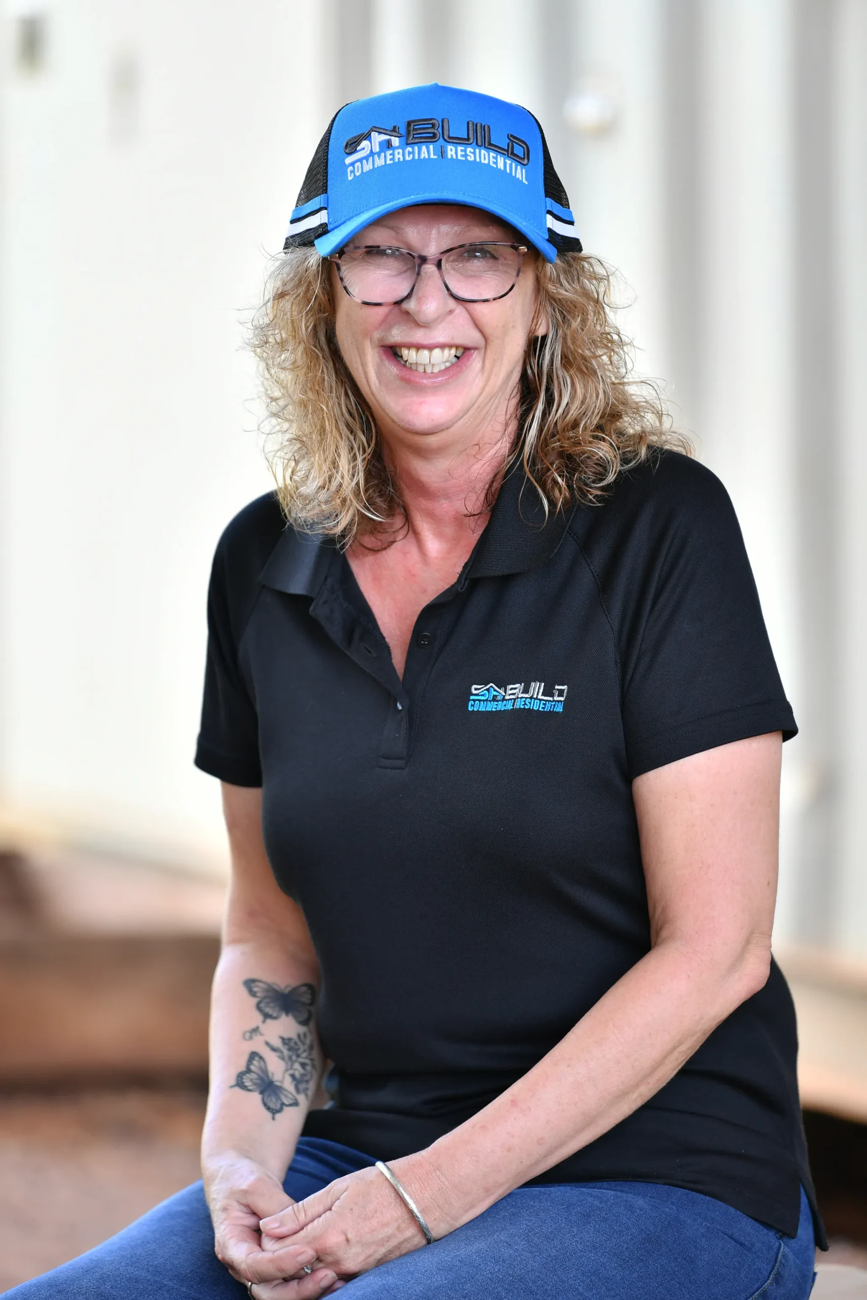 Smiling woman in casual work attire and cap.
