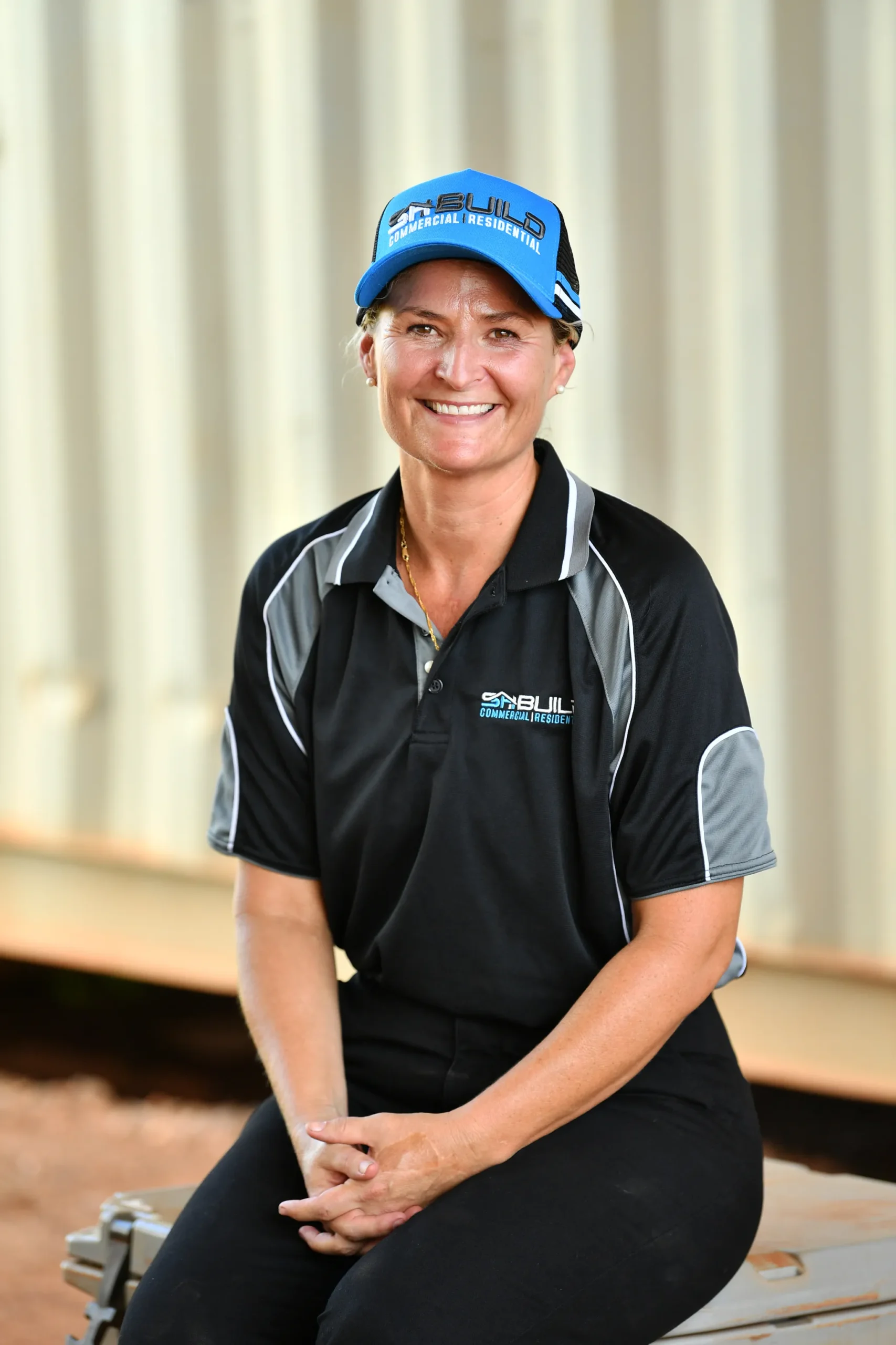 Smiling woman in work attire, wearing a cap.