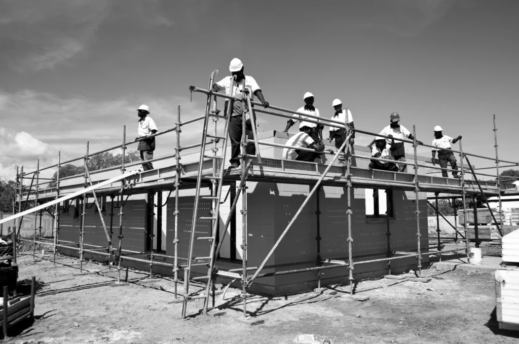 Construction workers on scaffolding at a building site.