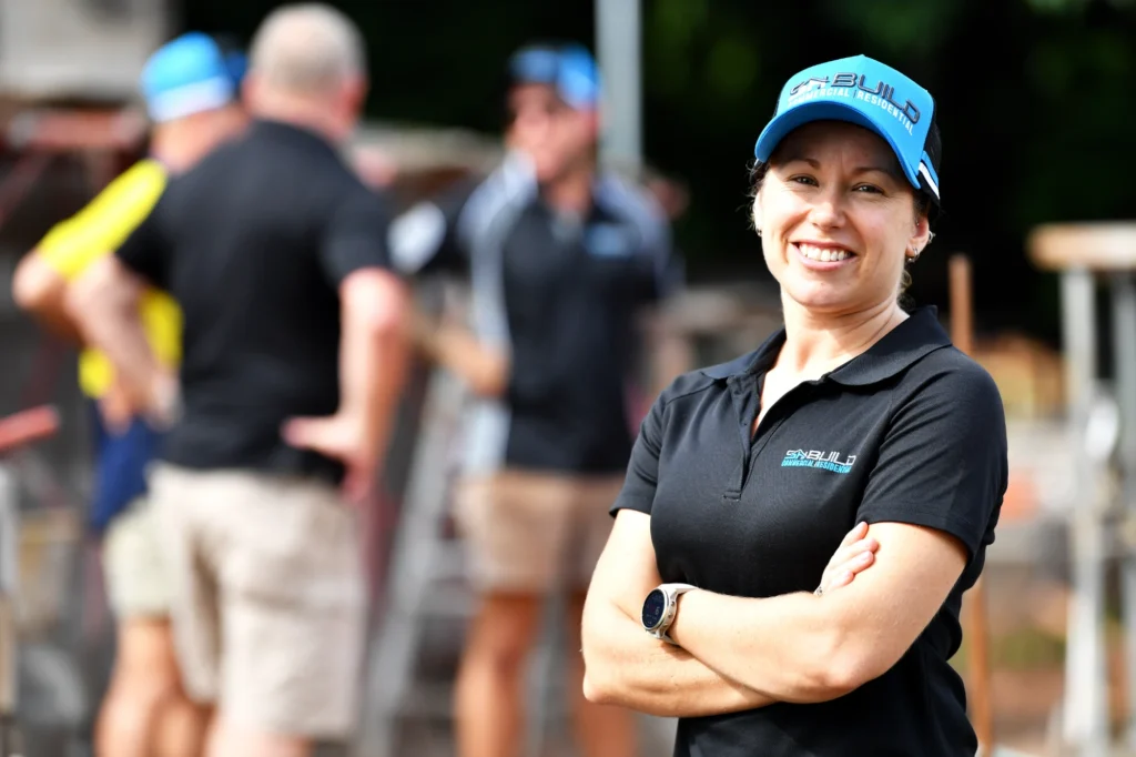 Smiling woman in work uniform at construction site.