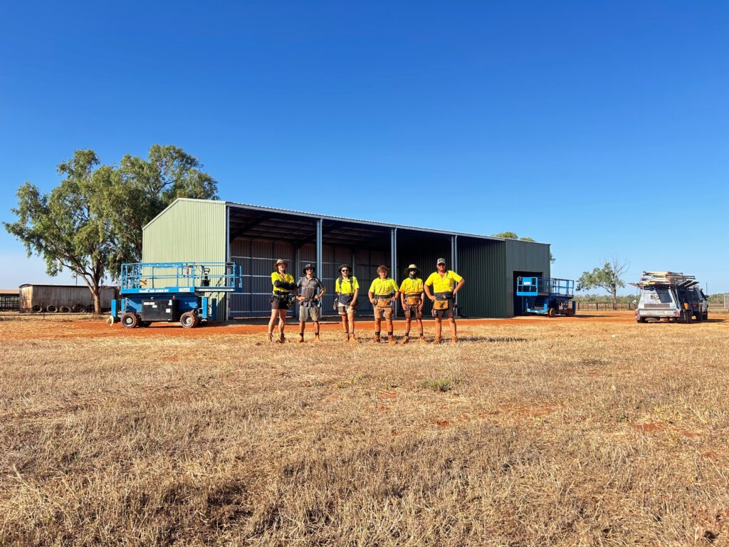 Workers in high-visibility shirts near a shed