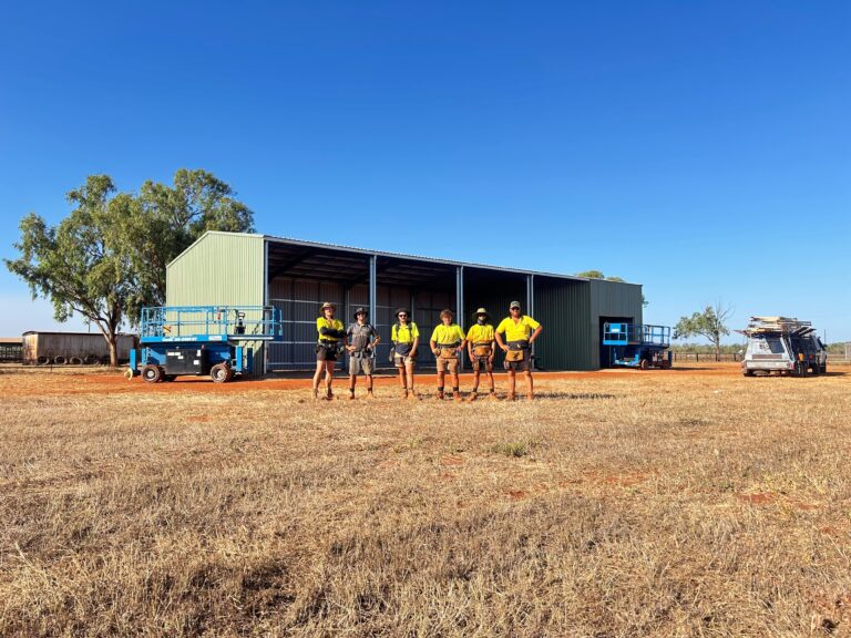 Workers in high-visibility shirts near a shed