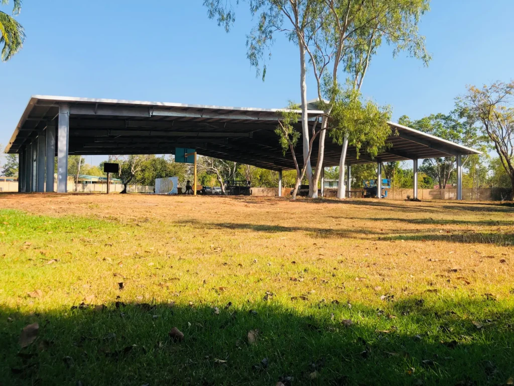 Large shaded outdoor structure with trees nearby.
