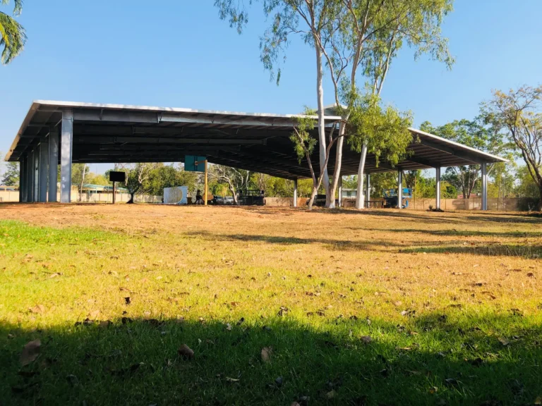 Large shaded outdoor structure with trees nearby.