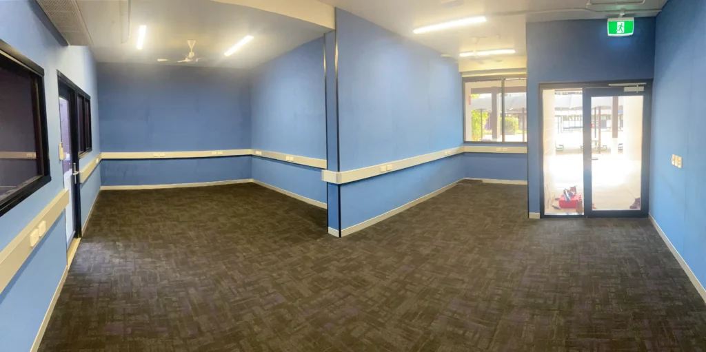 Spacious blue-walled room with carpeted flooring.