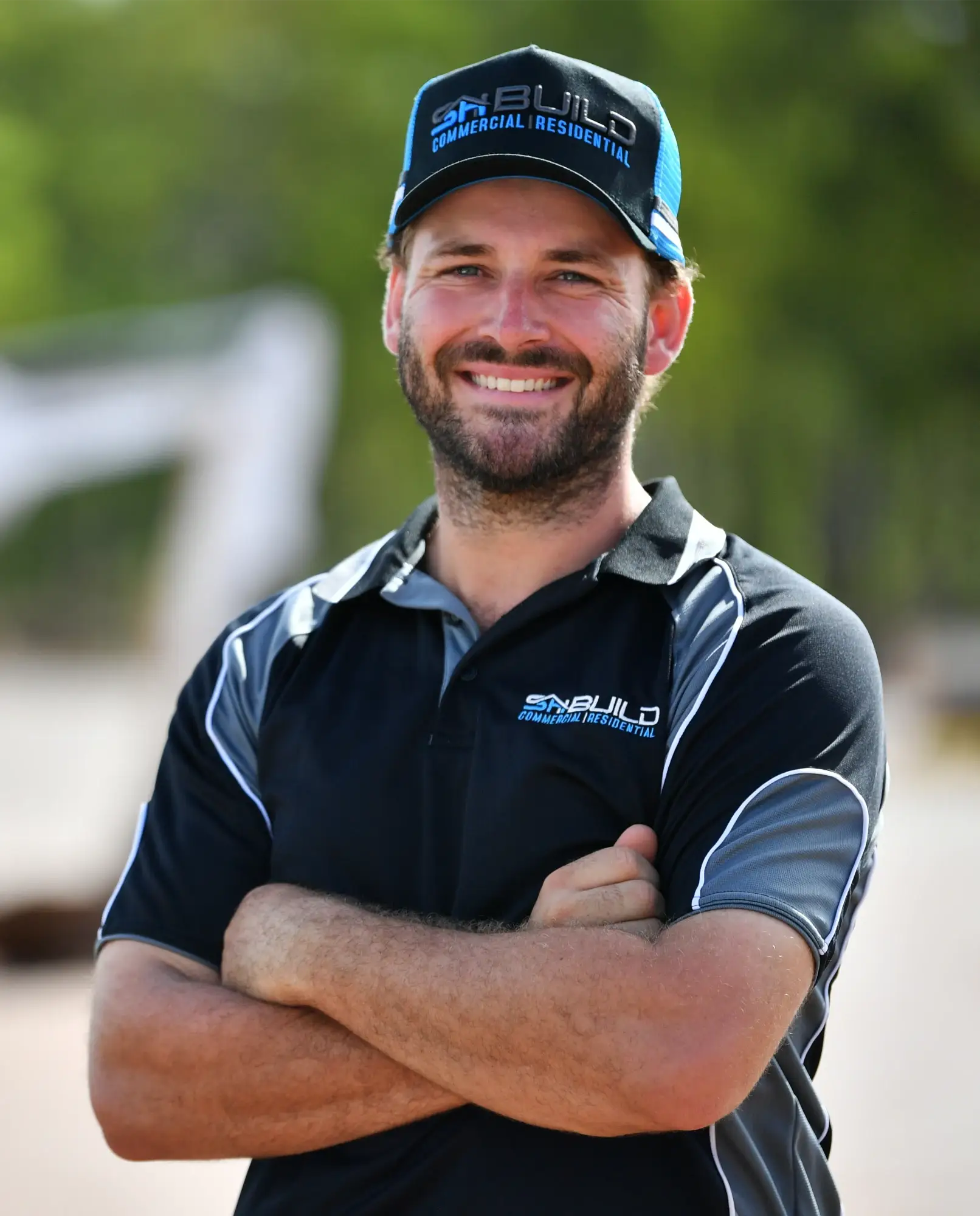 Smiling man in work attire with crossed arms.