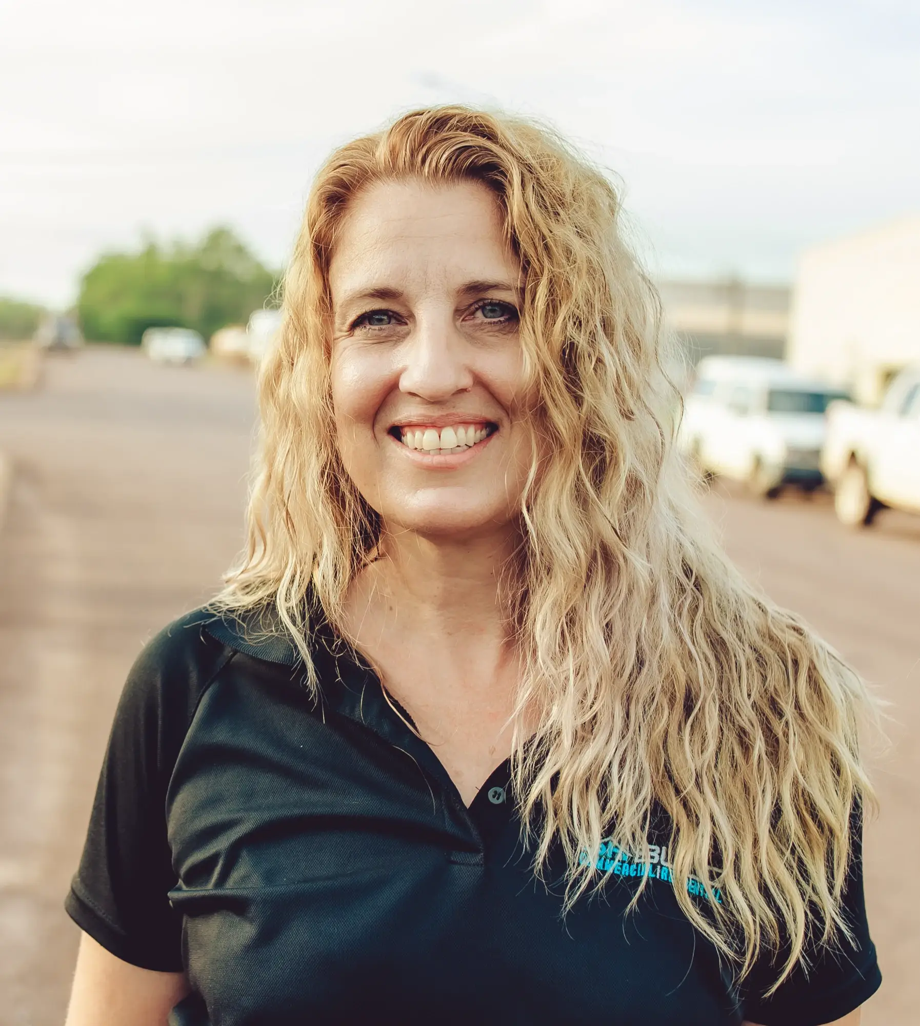 Smiling woman with curly blonde hair outdoors