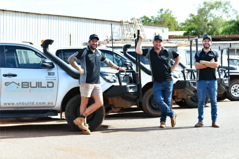 Three men beside work vehicles