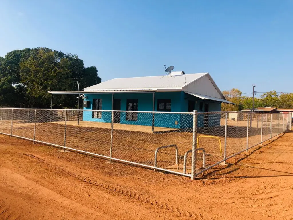 Turquoise house with white roof and chain fence